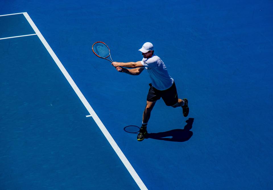 Tennis player hitting a backhand on a blue hard court