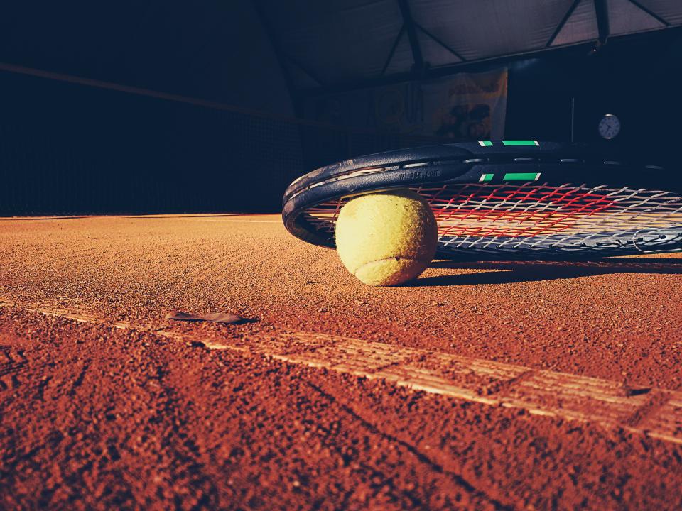 Tennis racket and ball on a clay court